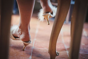 Donna con tacchi alti piumati, vista da dietro e vicino a una sedia. Drimage - Tropea - Reggio Calabria