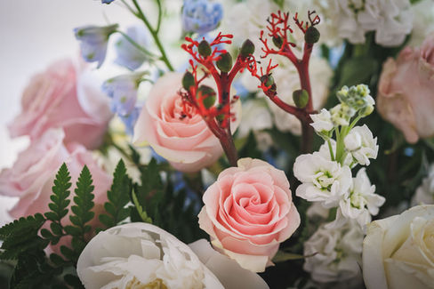 Close-up of pink roses, white flowers, and red stems; a beautiful bouquet.