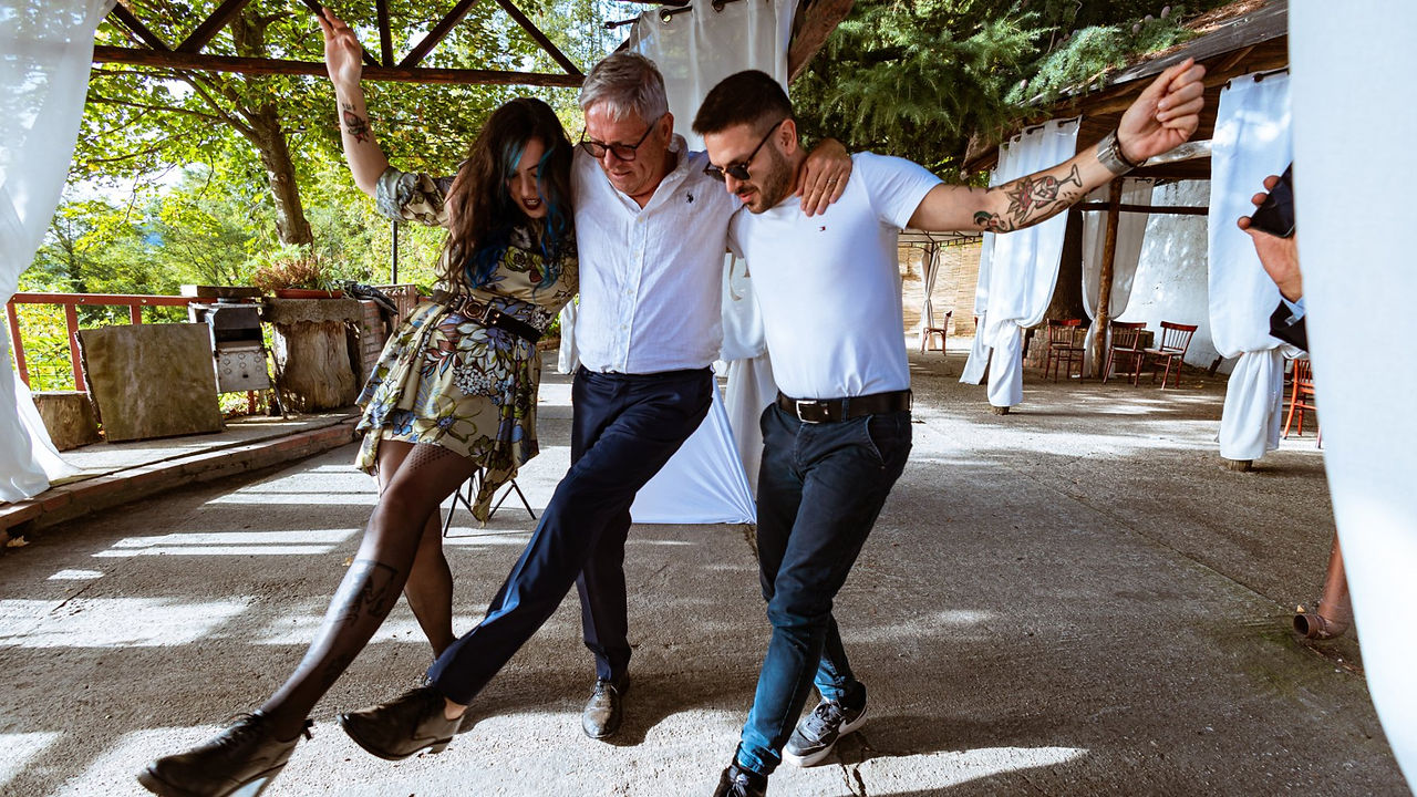 Tre persone ballano all'aperto senza pose, felici e spensierate durante una festa. Drimage