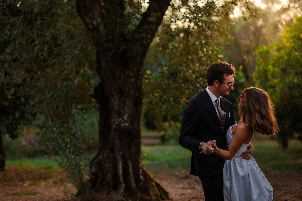 Fotografia di Drimage Creative studio di Simona Turano Photographer. Coppia in abiti eleganti che balla lentamente in un frutteto illuminato dal sole, tenendosi per mano e guardandosi negli occhi in un'atmosfera romantica.
