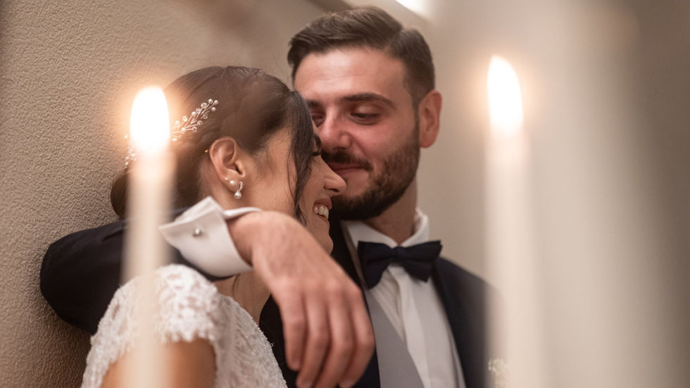 Smiling couple embracing, in love. Matrimonio elegante e romantico. Close up, candles in background.