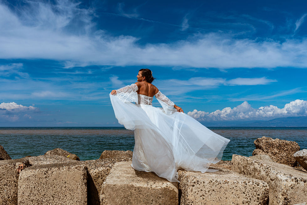 Foto Sposa sugli scogli con il vento che fa volare il vestito da cerimonia