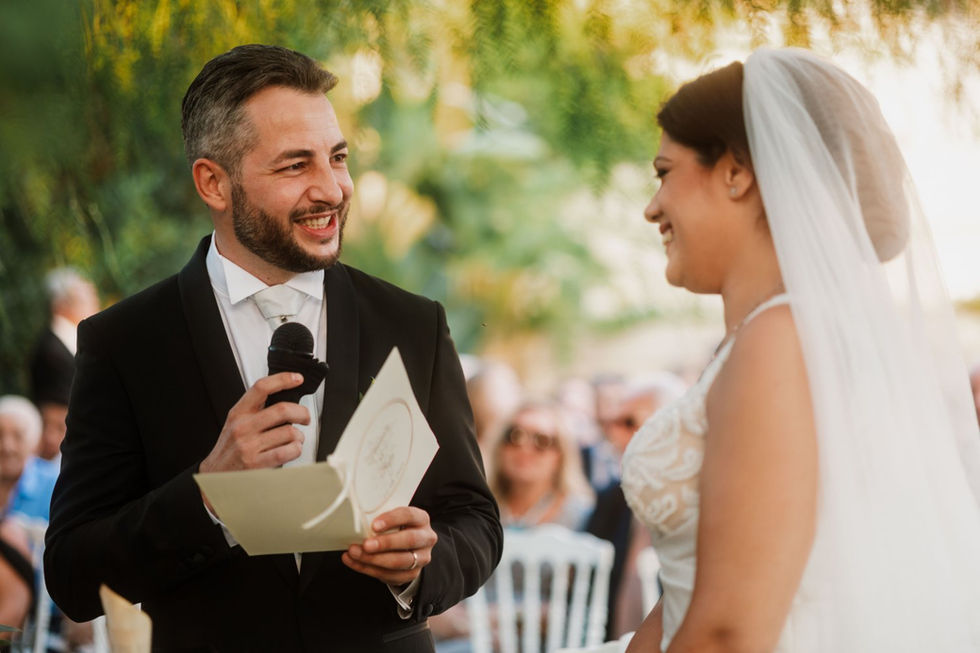 Uomo officiante parla alla sposa sorridente durante la cerimonia nuziale.