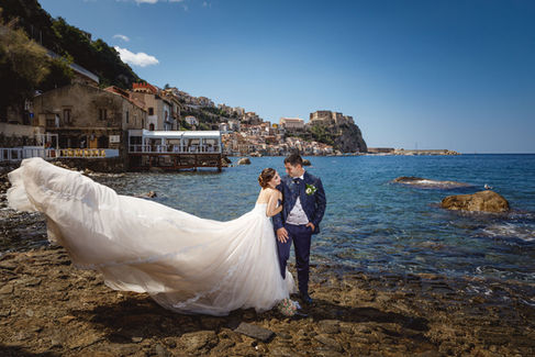 Coppia di sposi con abito bianco e blu, mare e monti. Matrimonio mare e monti, sullo sfondo