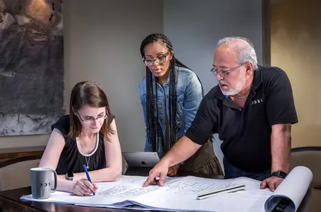 Team reviewing blueprints in a planning session highlights structured collaboration in corporate lifestyle settings.