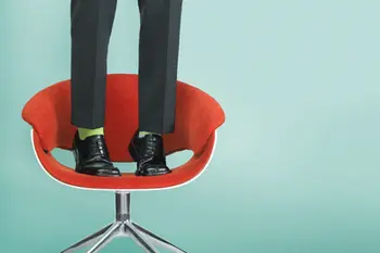 Man in green socks stands on red chair for quirky lifestyle product photography.