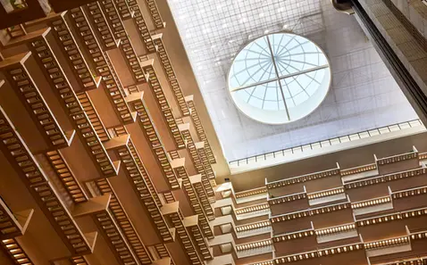 View looking up inside a hotel atrium with geometric balconies and a large circular skylight ceiling.