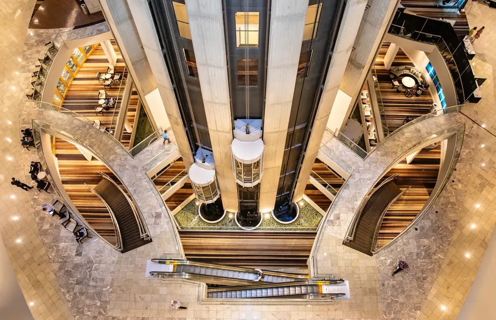 Aerial photography of a modern building interior with glass elevators and curved architecture.