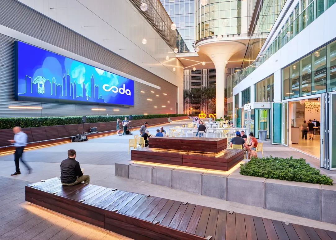 Coda building’s exterior plaza with modern seating, string lights, and people enjoying the space in Atlanta.