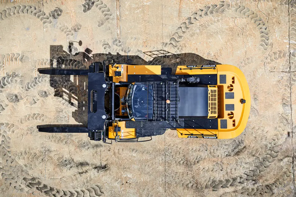 Drone aerial photography of a yellow forklift parked on concrete with layered tire tracks around it.
