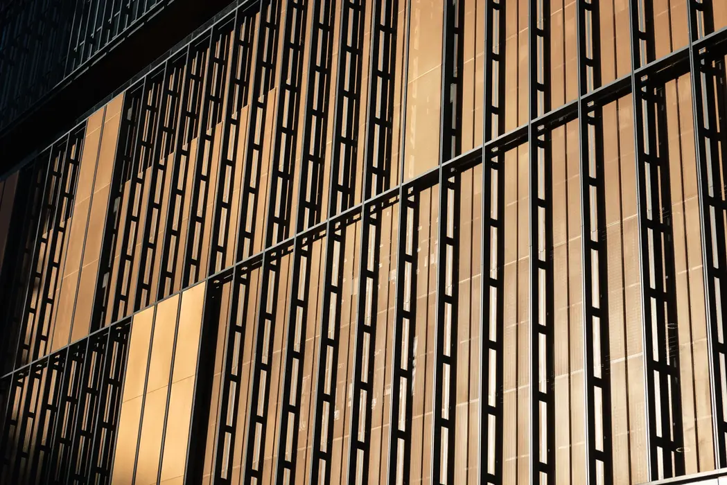 Aerial drone photography of a building facade with vertical slats and dramatic light-shadow contrast.