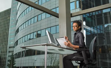 A focused woman reviews her planner at a desk with city views, reflecting productivity in corporate lifestyle offices.