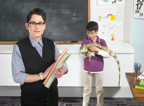 Teacher holds books while student handles iguana in lifestyle product photography.