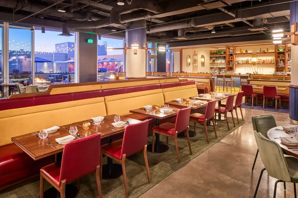 Interior design photography of the SLC Hyatt restaurant with bold color seating, wood accents, and city views through expansive windows. Keywords: interior design photography, commercial interior photography, SLC Hyatt.