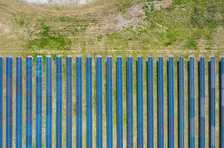 High resolution aerial photography of solar panel rows in a large symmetrical solar farm.