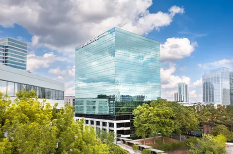 Anthem Midtown tower rising over busy Atlanta highway with sunset reflections, captured in commercial exterior architectural photography.