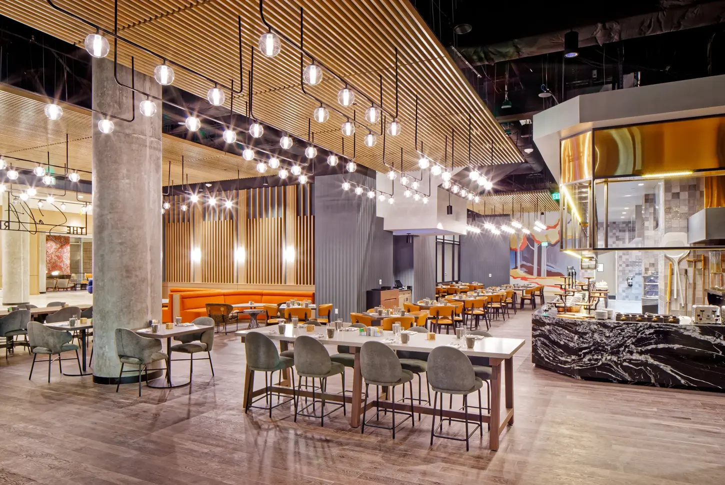 Hyatt Salt Lake City restaurant interior at night with hanging lights, warm wood accents, and orange seating.