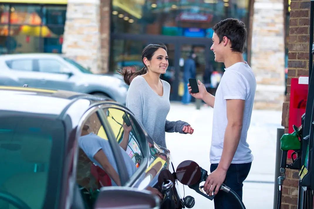 Young couple chats by car while pumping gas at a station for lifestyle product photography.