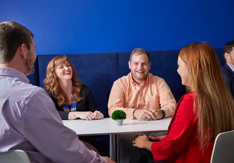 Coworkers laugh during a relaxed meeting, showcasing informal teamwork as part of a vibrant corporate lifestyle.