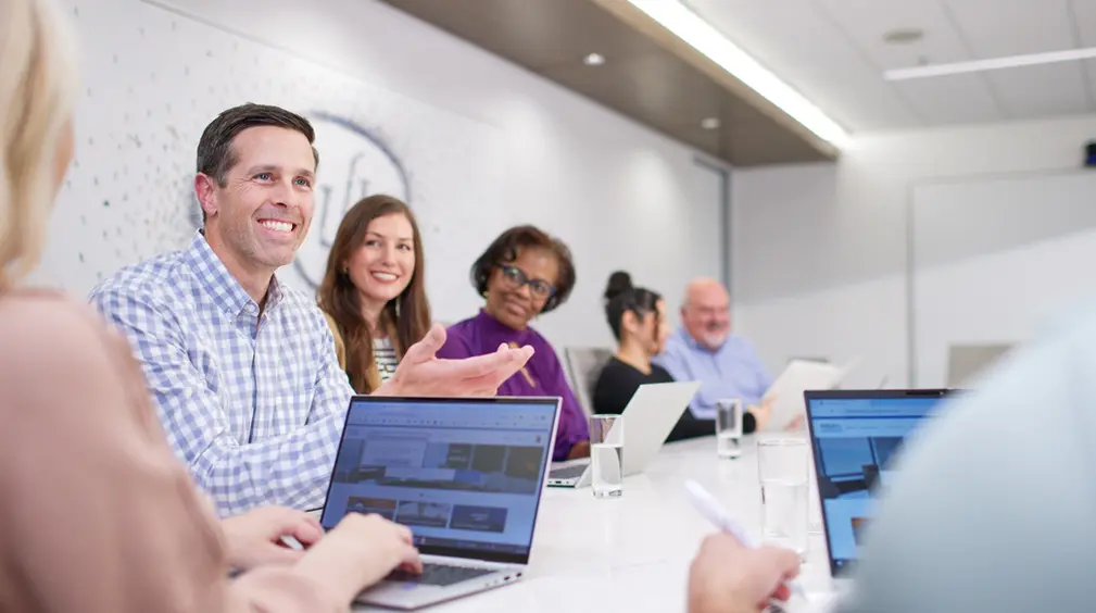 Colleagues laugh during a creative meeting, capturing the energy and connection found in corporate lifestyle culture.