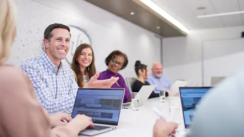 Colleagues laugh during a creative meeting, capturing the energy and connection found in corporate lifestyle culture.