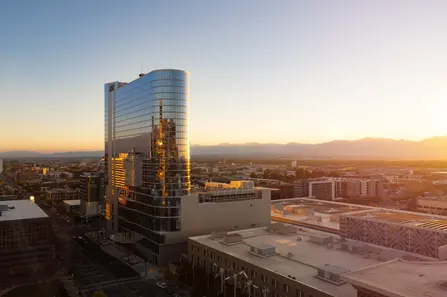 SLC Hyatt hotel reflecting sunset light in a cityscape with mountain views.