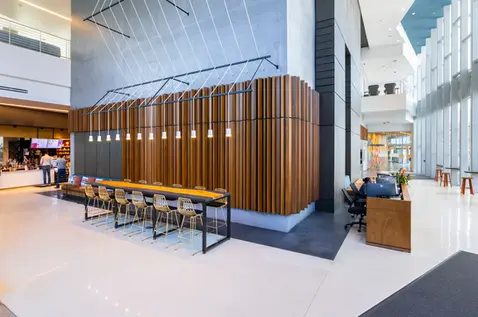 Communal table in CODA lobby with sculptural wood paneling and pendant lighting — modern commercial interior captured through interior design photography.