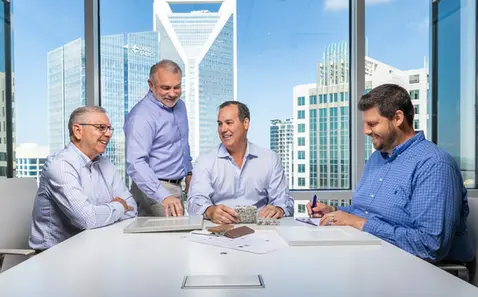 Business professionals meet at a boardroom table with city views, showing leadership in corporate lifestyle settings.