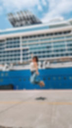 woman jumping in the air in front of the Celebrity Apex Cruise ship at the port 