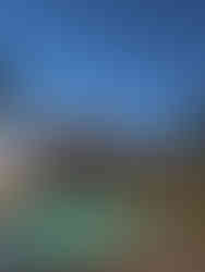 a pool illuminated under a twilight sky with a resort tower and palm trees surrounding the pool