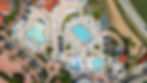 aerial view over the multiple pools and water slides surrounded by lounge chairs, umbrellas, and palm trees at the omni la costa resort 