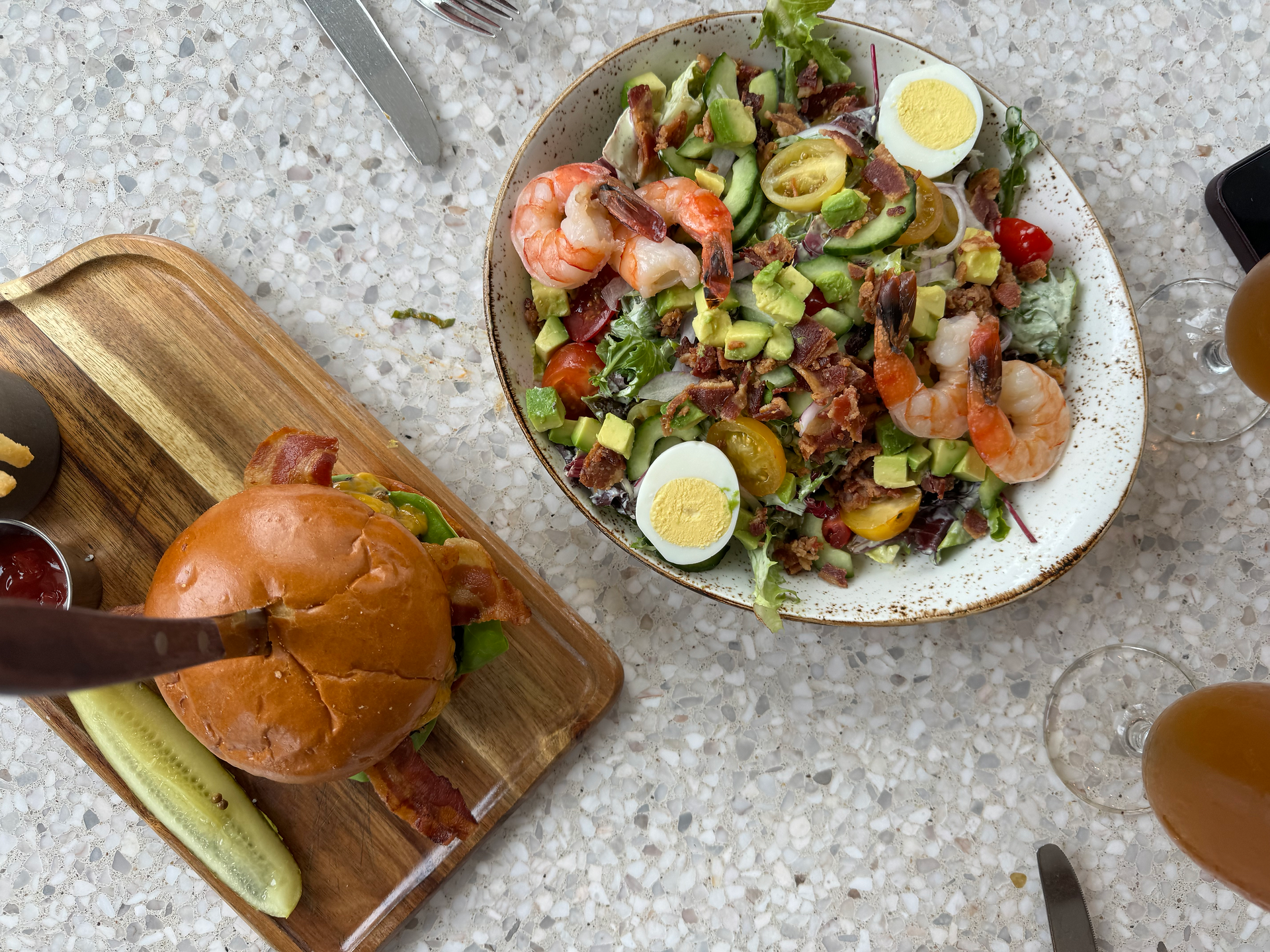 top down view of a bacon cheese burger and a shrimp louie salad 