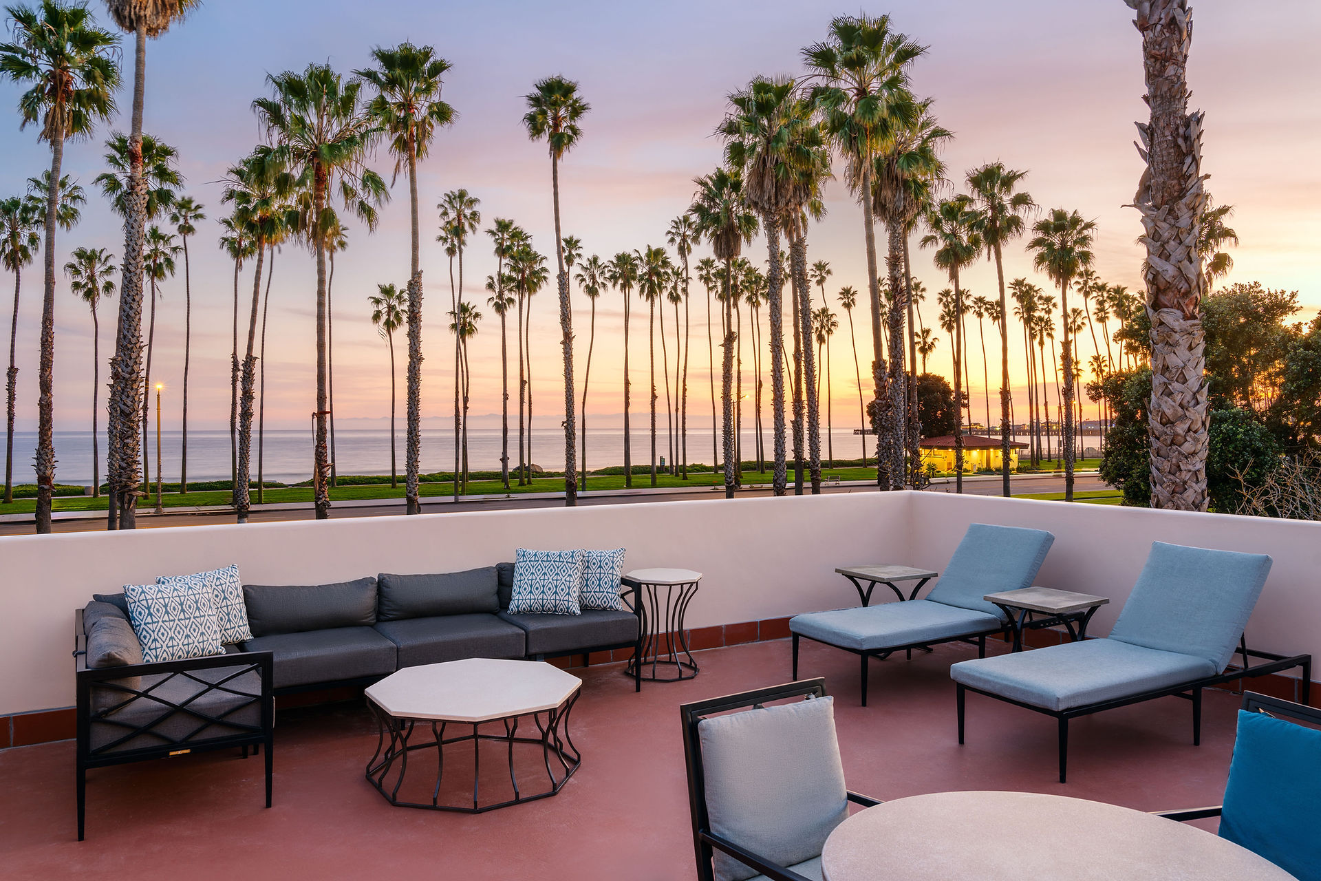 Sunset skies over palm trees from the large suite balcony at the Hilton Santa Baraba with outdoor couches and lounge chairs 