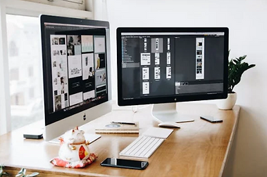 A clean computer setup on a nice wooden desk with a website being created on the computer