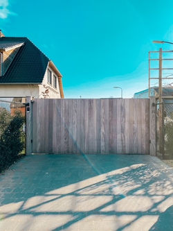 Automatische houten schuifpoort op rail afrormosia verticale planken op de kader tand en g