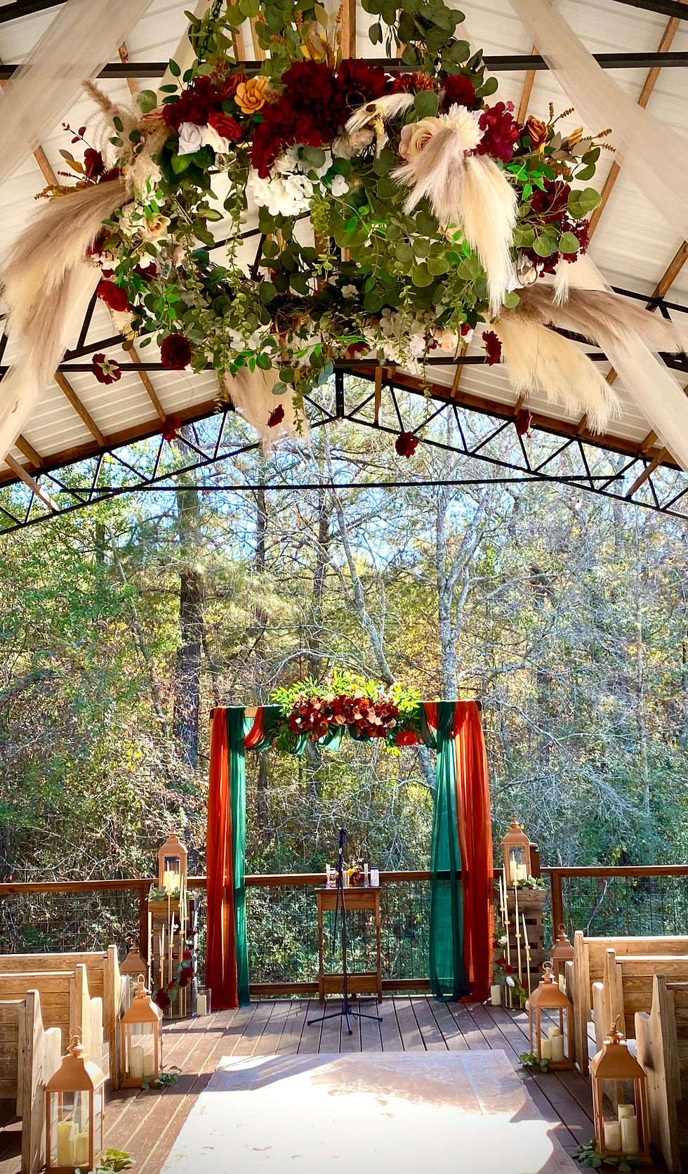Eye-level view of a small outdoor wedding setup with floral decorations and a wooden arch