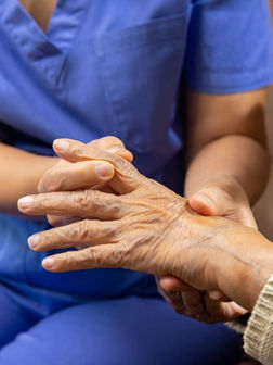 Profesional de salud ayudando a paciente con artritis reumatoide en manos
