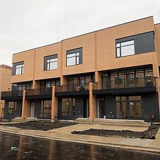 Front view of a brick residential construction project with black balconies