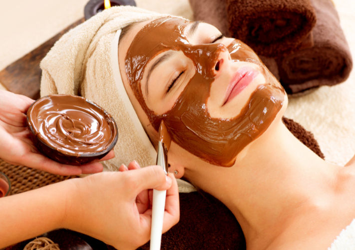 Mujer recibiendo mascarilla de chocolate, FACIAL CHOCOLATERAPÍA en spa.