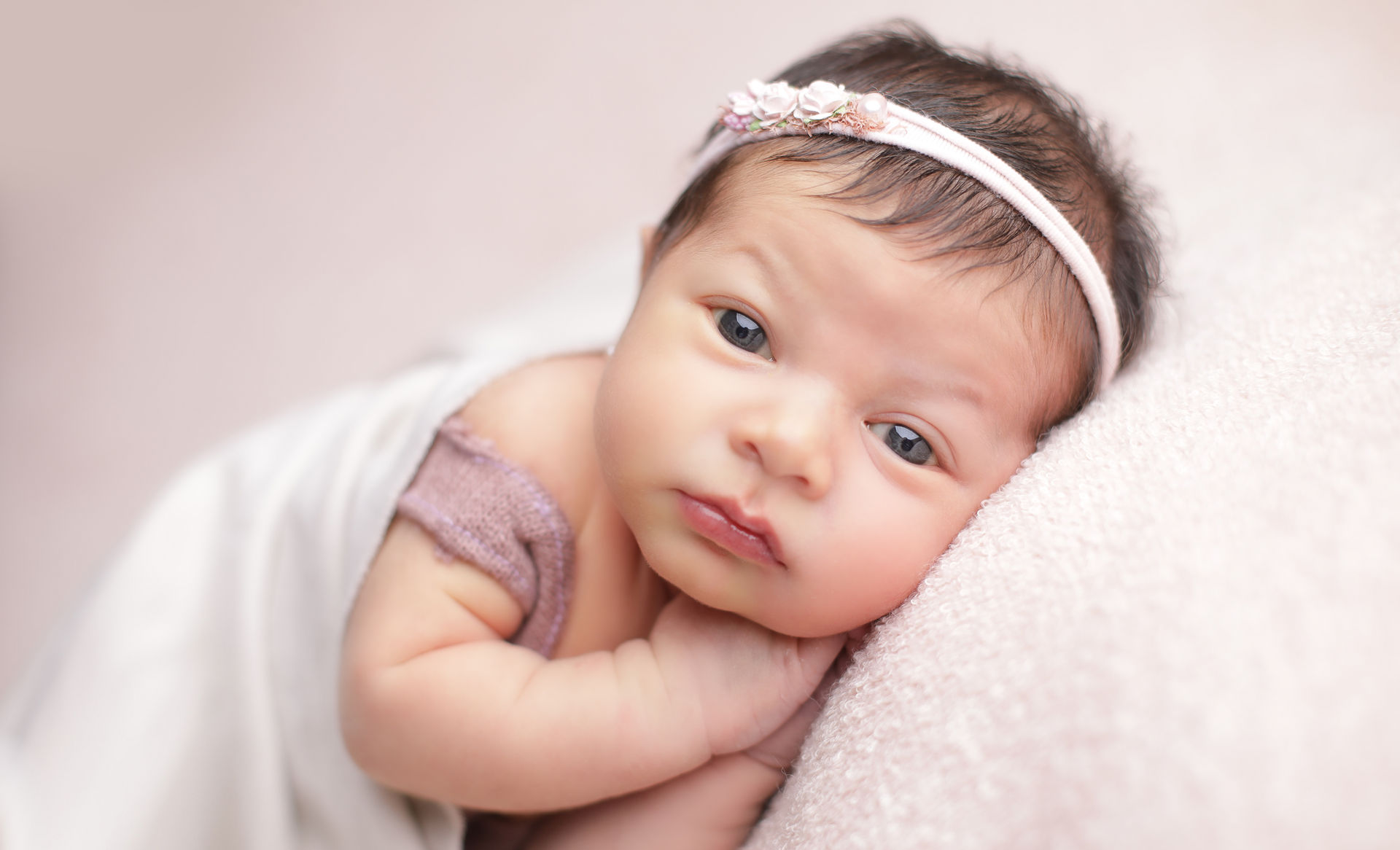 Recién nacido en decoración rosada, con los ojos abiertos
