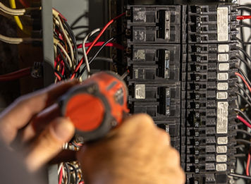 Electrician is installing an electrical circuit breaker in a power panel using drill
