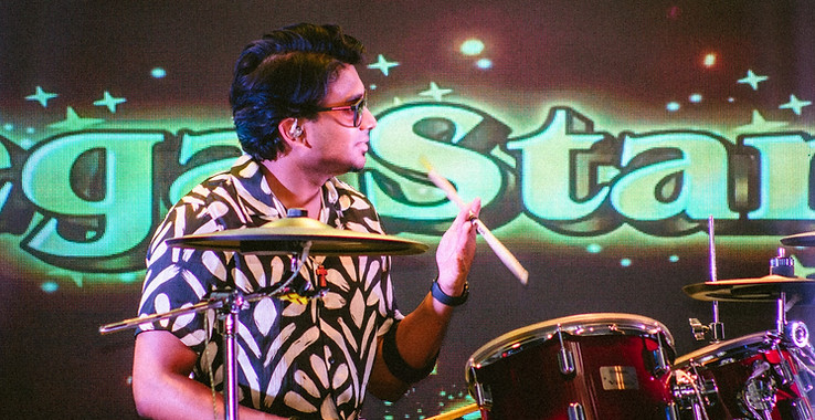 Drummer on stage ready to perform with a screen in the background