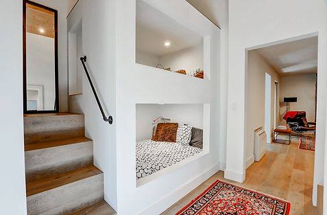 Built-in bunk beds in Woodstock cabin designed by NYC interior designer with wood platform and striped cushions