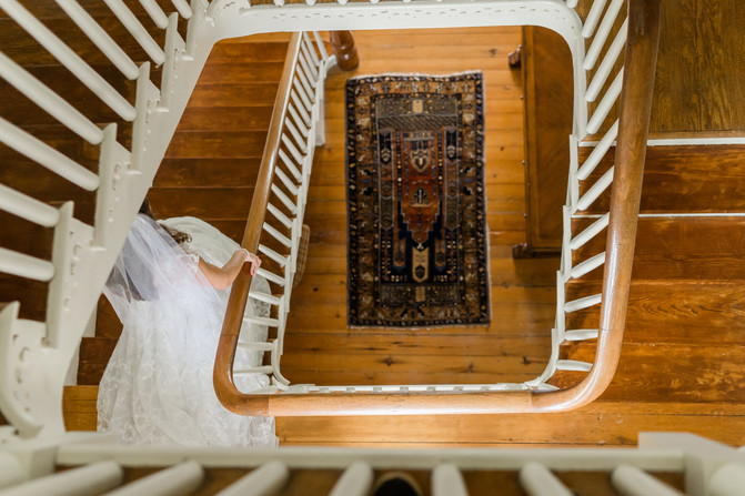 View looking down the center of a spiral staircase as a bride is walking down the stairs inside of Stepne Manor