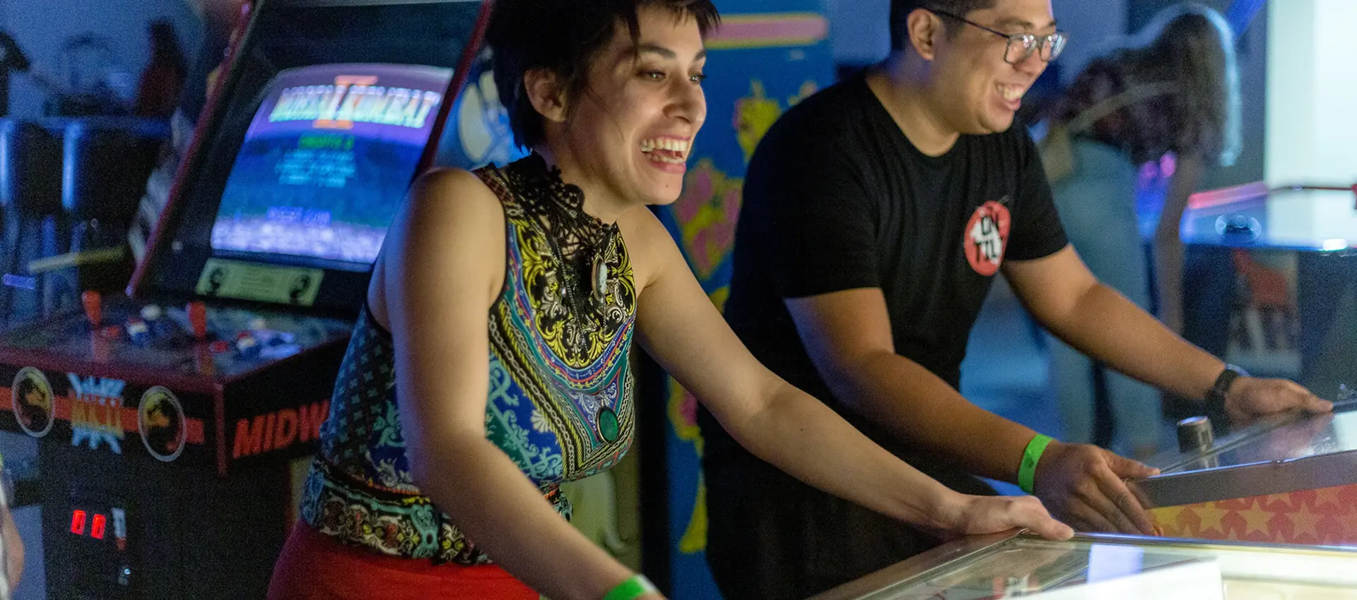 a couple smiling playing pinball machines