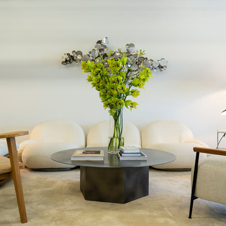 Vibrant green flowers vase books on a table in front of white sofa