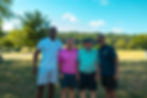 Four men smiling together on a sunny golf course.