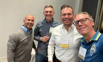 Four men smiling for a group photo at a conference