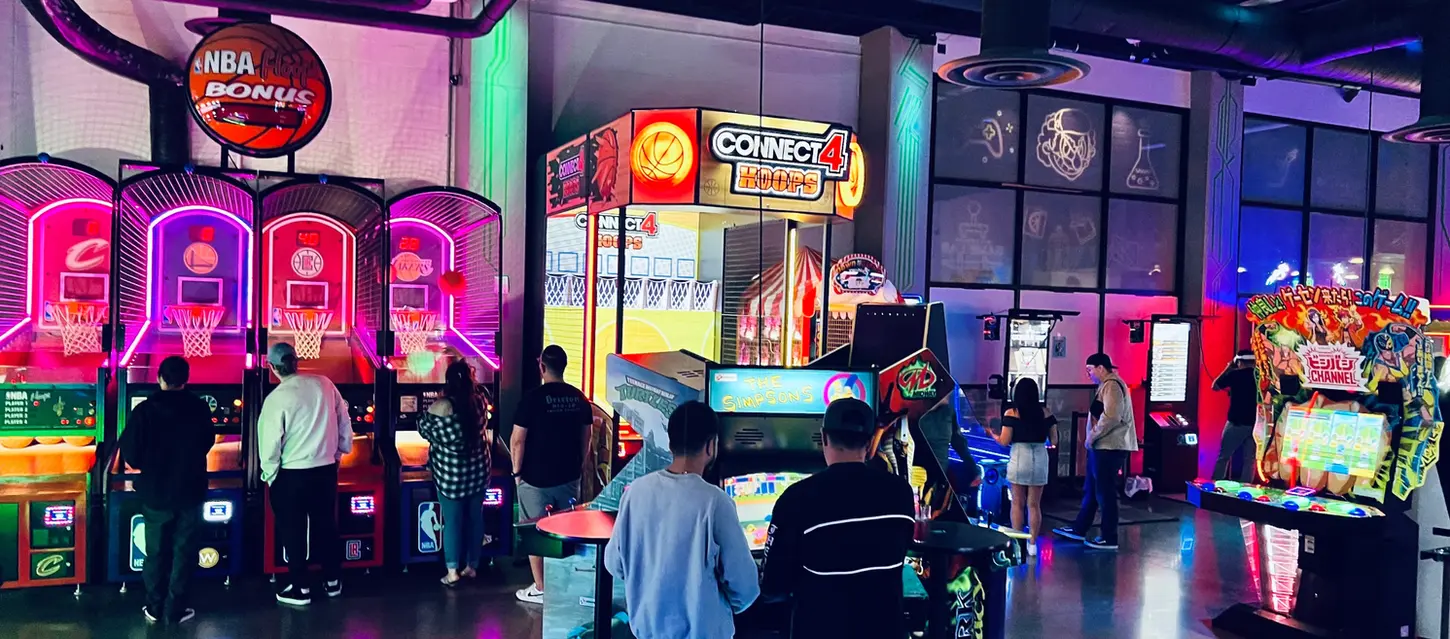 People playing arcade games with NBA Bonus and Connect 4 signs at the arcade