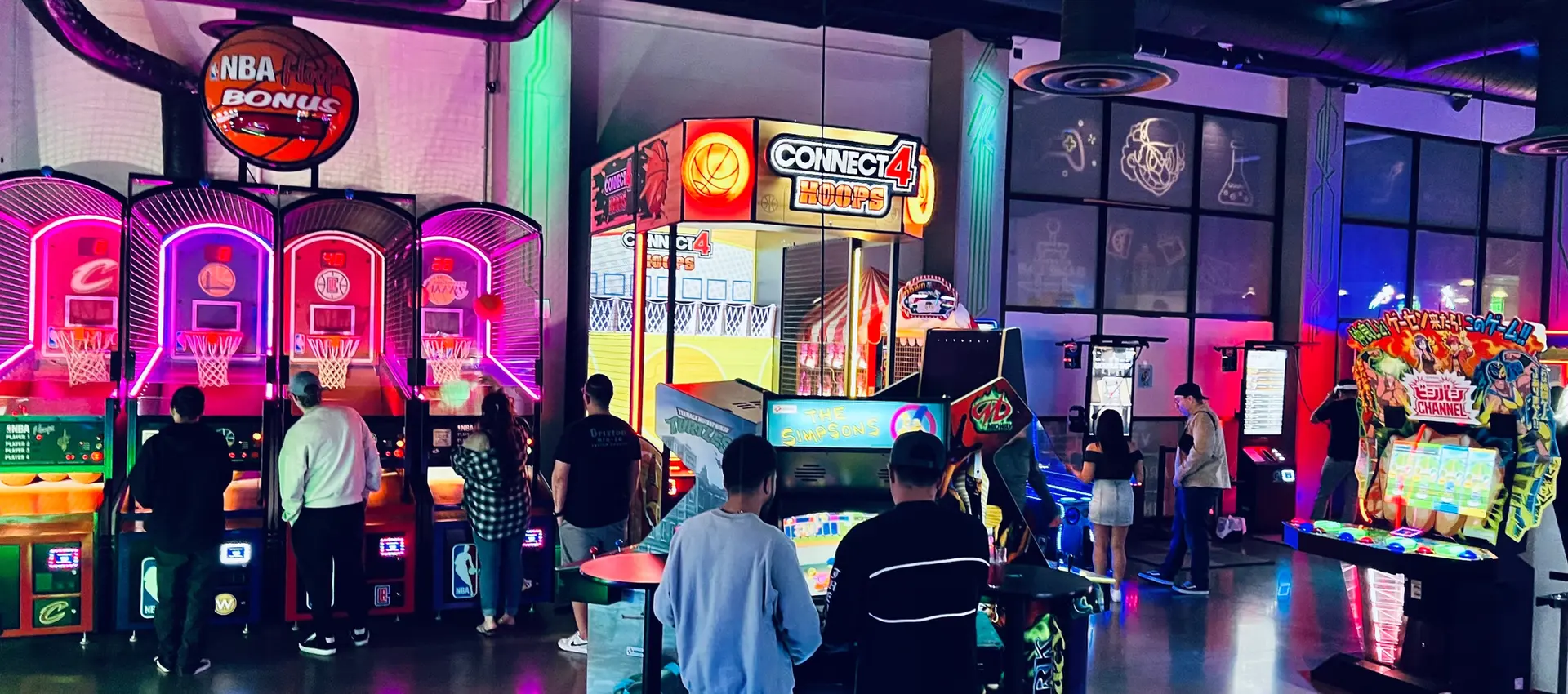 People playing arcade games with NBA Bonus and Connect 4 signs at the arcade